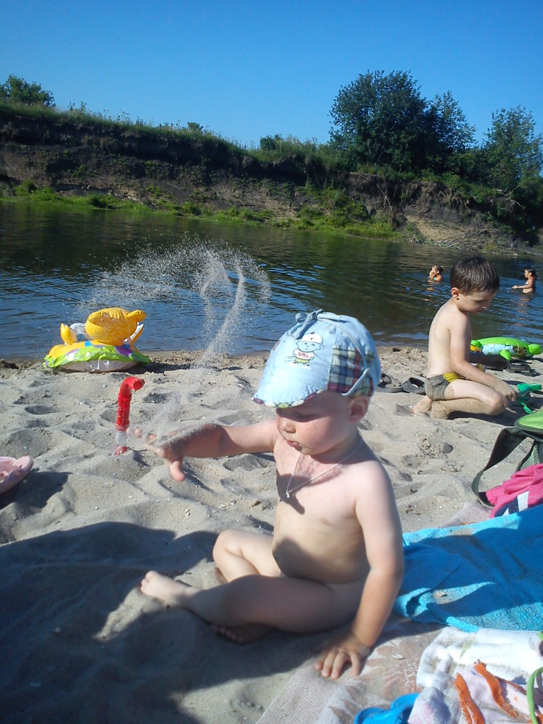 Малыш играет в песок на реке