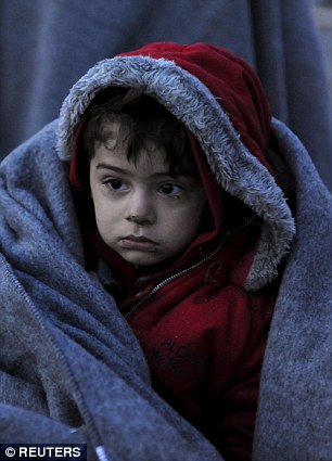 Another is covered with a blanket as he waits to cross the Greek-Macedonian border